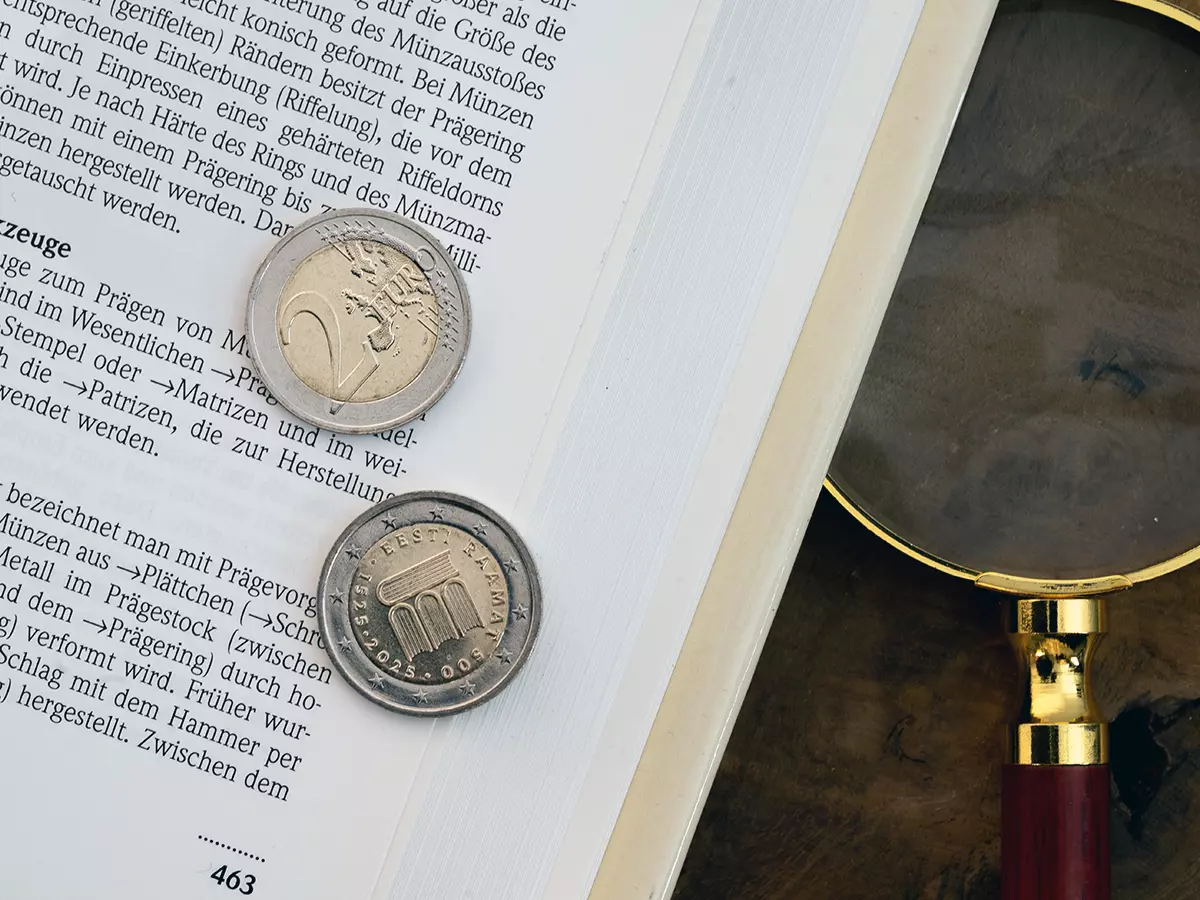 2-Euro Münze auf einem Buch und eine Lupe